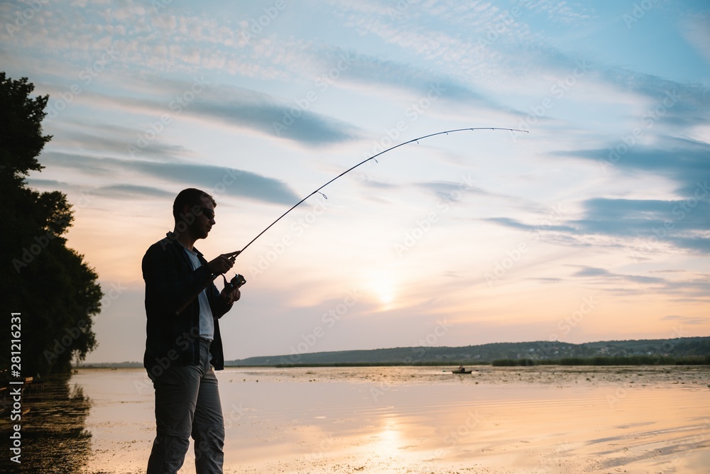 Fishing. spinning at sunset. Silhouette of a fisherman