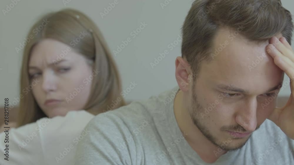 Close-up portrait of sad man and woman sitting back to back with unhappy faces at home. Problems in the relationship. Betrayal, mistrust, breakup concept. Misunderstanding in family. Close-up portrait of sad man and woman sitting back to back with unhappy faces at home. Problems in the relationship. Betrayal, mistrust, breakup concept. Misunderstanding in family.