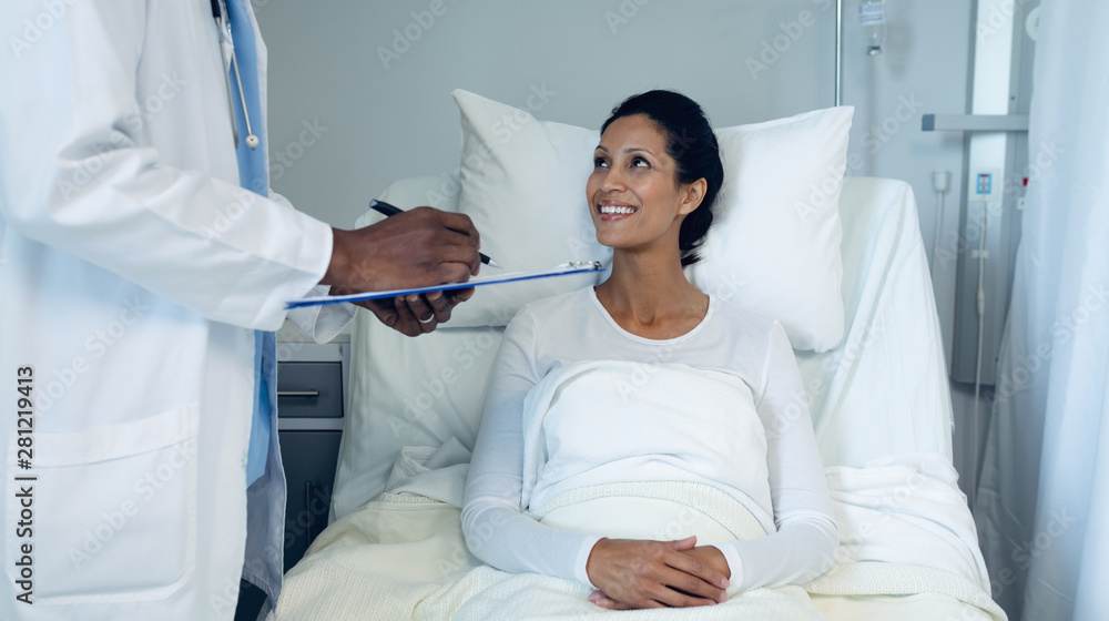 Male doctor interacting with female patient in the ward Male doctor interacting with female patient in the ward