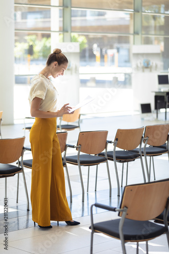 Caucasian female executive looking at documents while standing in empty conference room