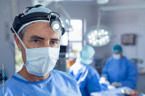 Bild auf Leinwand Male surgeon with surgical headlight standing in operation room