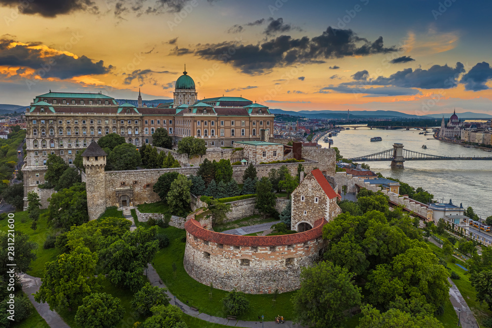 Budapest, Hungary - Aerial view of the famous Buda Castle Royal Palace with Szechenyi Chain Bridge and Hungarian Parliament building at sunset time with colorful sky