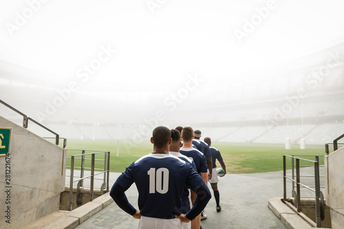 Diverse male rugby players standing at the entrance of stadium in a row for match