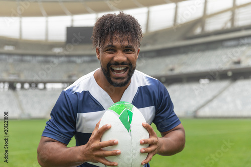 Happy African American Rugby player standing with rugby ball in stadium