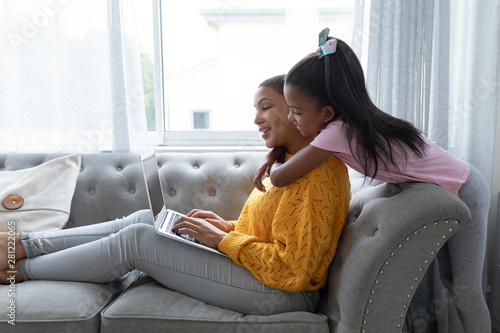 Mother and daughter embracing each other on a sofa in living room