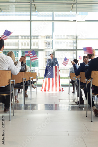 Group of diverse business people with flags listening mature businessman presentation
