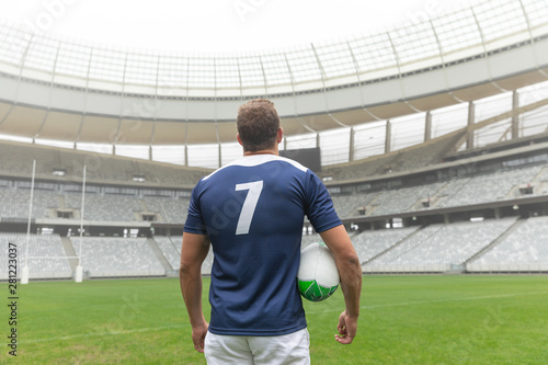 Caucasian rugby player standing with rugby ball in stadium