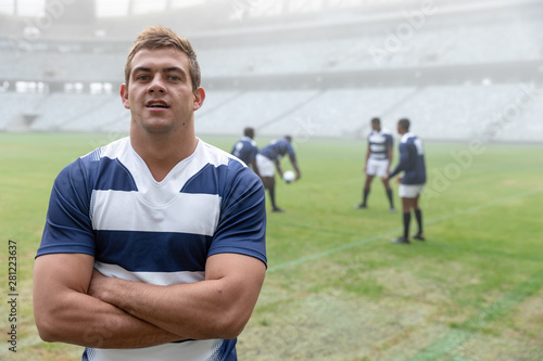 Caucasian Male rugby player standing with arms crossed in stadium