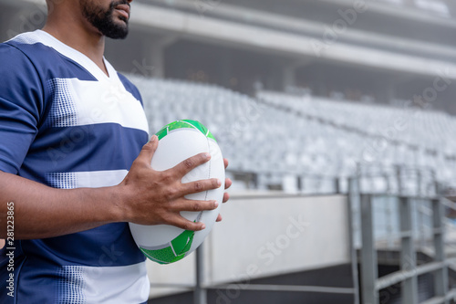 African American male rugby ball player holding a rugby ball in stadium