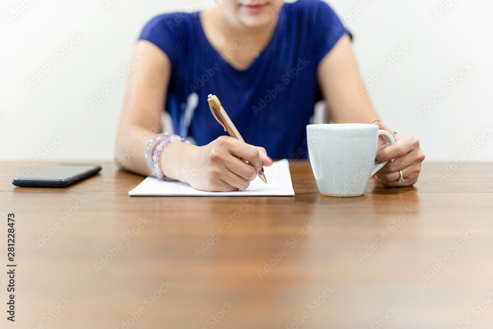 Businesswoman hand writing on paperwork with cup of coffee on working desk. Businesswoman hand writing on paperwork with cup of coffee on working desk.