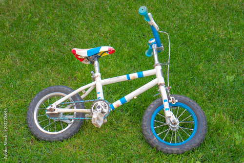 A children's bike is lying on the green grass on a Sunny day
