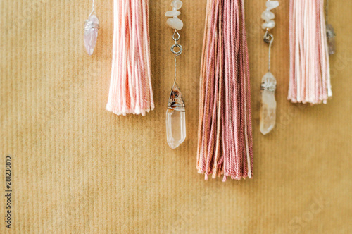 Closeup modern mandala with quartz crystals, amethyst, moonstone, tassels and chain on craft paper background © pliekhova