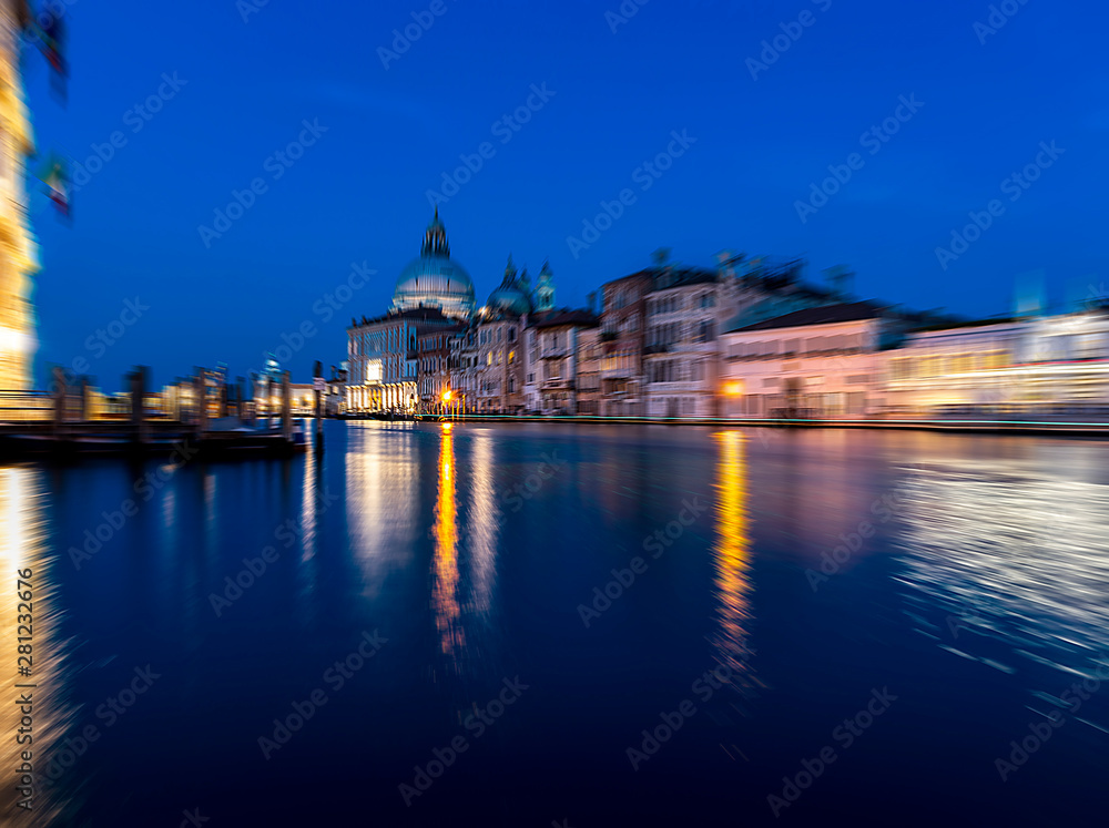 View of Grand Canal and Basilica della Salute at night with boat night trails with radial blur