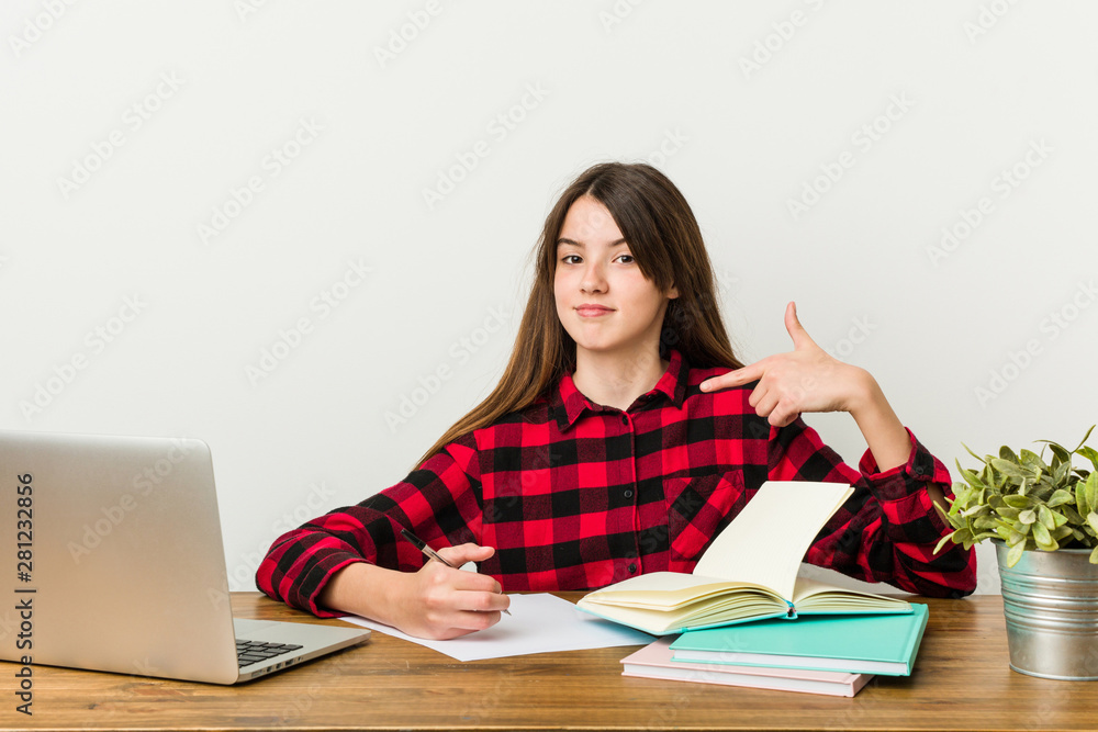 Young teenager going back to her routine doing homeworks person pointing by hand to a shirt copy space, proud and confident Young teenager going back to her routine doing homeworks person pointing by hand to a shirt copy space, proud and confident