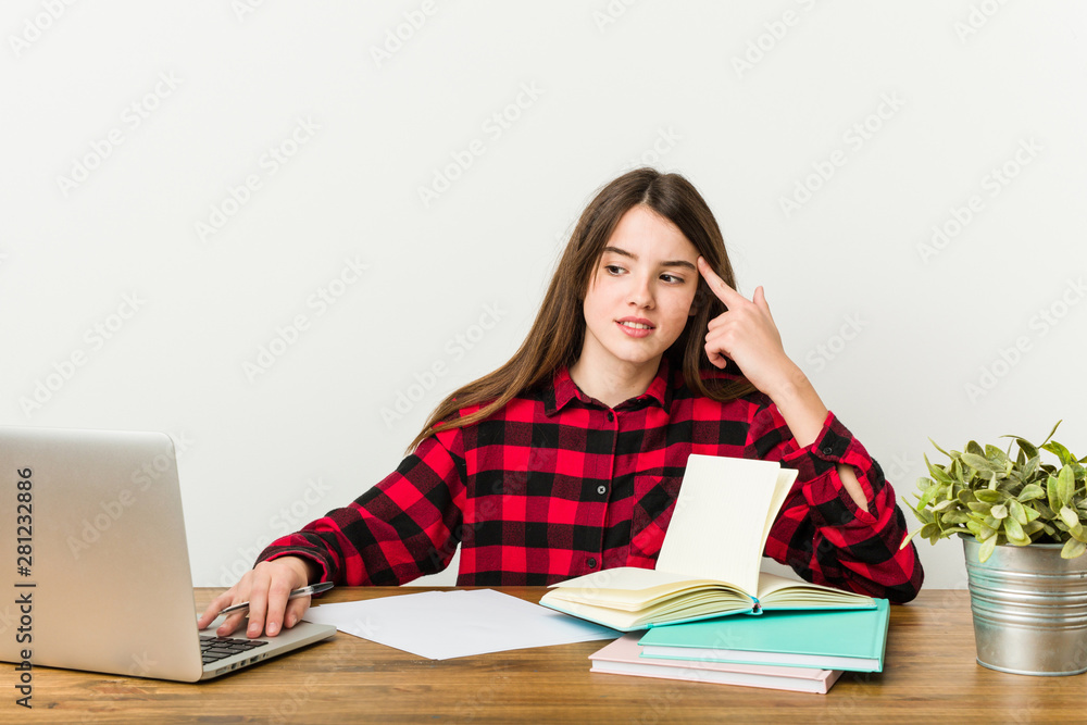 Young teenager going back to her routine doing homeworks showing a disappointment gesture with forefinger. Young teenager going back to her routine doing homeworks showing a disappointment gesture with forefinger.