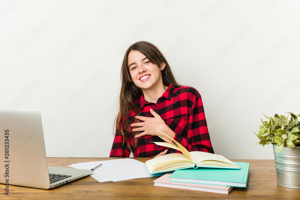 Young teenager going back to her routine doing homeworks laughs happily and has fun keeping hands on stomach. Young teenager going back to her routine doing homeworks laughs happily and has fun keeping hands on stomach.