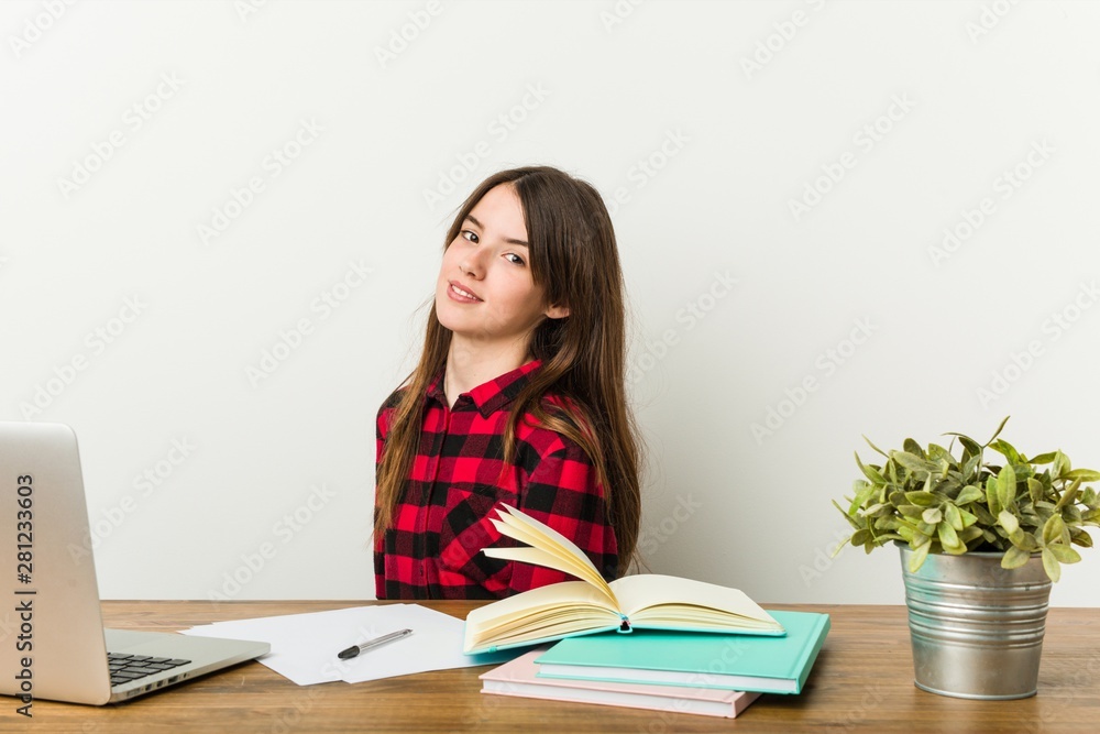 Young teenager going back to her routine doing homeworks looks aside smiling, cheerful and pleasant. Young teenager going back to her routine doing homeworks looks aside smiling, cheerful and pleasant.