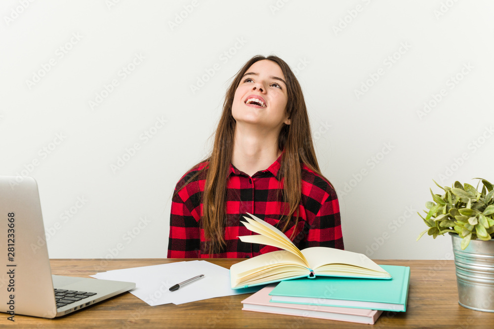 Young teenager going back to her routine doing homeworks relaxed and happy laughing, neck stretched showing teeth. Young teenager going back to her routine doing homeworks relaxed and happy laughing, neck stretched showing teeth.
