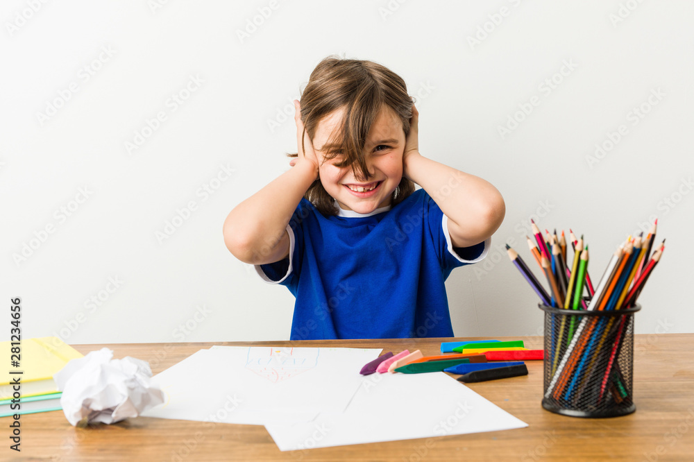 Little boy painting and doing homeworks on his desk covering ears with hands trying not to hear too loud sound. Little boy painting and doing homeworks on his desk covering ears with hands trying not to hear too loud sound.