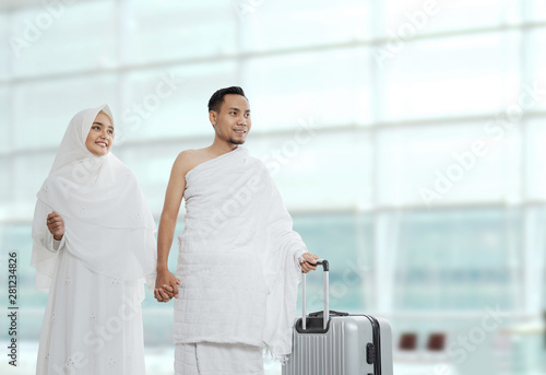 muslim couples wife and husband wearing white traditional clothes for Ihram ready for Hajj walk in the airport photo