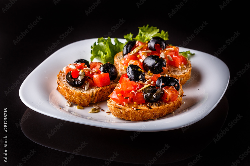 Italian bruschetta with tomato, black olives, lettuce and mustard Italian bruschetta with tomato, black olives, lettuce and mustard