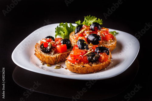 Italian bruschetta with tomato, black olives, lettuce and mustard