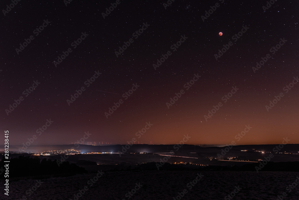 Fototapeta premium Sonnenuntergang in der Berglandschaft mit Mondfinsternis