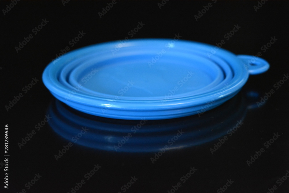 Blue folding and multifunctional rubber plate, a bowl with a plastic edging on a black glossy surface. Blue folding and multifunctional rubber plate, a bowl with a plastic edging on a black glossy surface.