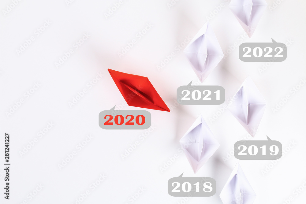 The new year 2020 floating away from succession years 2021, 2022. Red paper boat among other white.