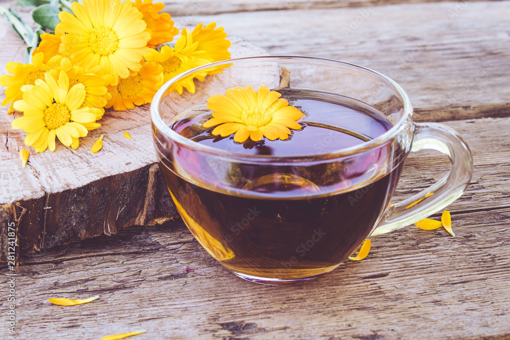 Herbal tea from calendula flowers in a transparent glass mug. Extract of tincture of calendula in the cup. Herbal tea from calendula flowers in a transparent glass mug. Extract of tincture of calendula in the cup.