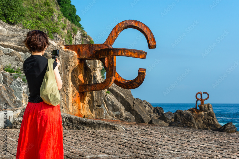 Fototapeta premium Woman taking photos at the Comb of the Wind in Donostia-San Sebastian, Spain