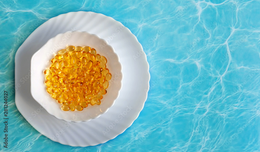 fish oil capsules in a white dish on a blue background fish oil capsules in a white dish on a blue background