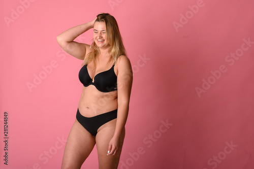 Beautiful fat girl in black lingerie on pink background