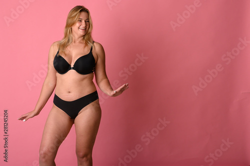 Beautiful fat girl in black lingerie on pink background