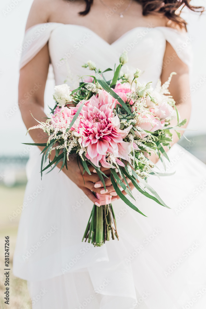 Stylish bride with a wedding bouquet in his hands with pink flowers and succulents Stylish bride with a wedding bouquet in his hands with pink flowers and succulents