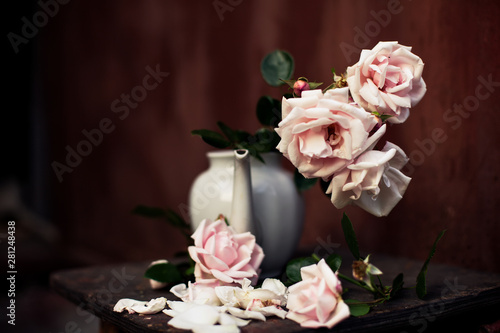  bouquet of pale pink roses in   white teapot vase. 