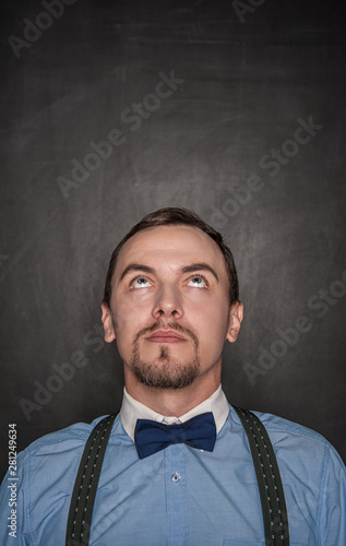 Thoughtful businessman or teacher looking up on blackboard