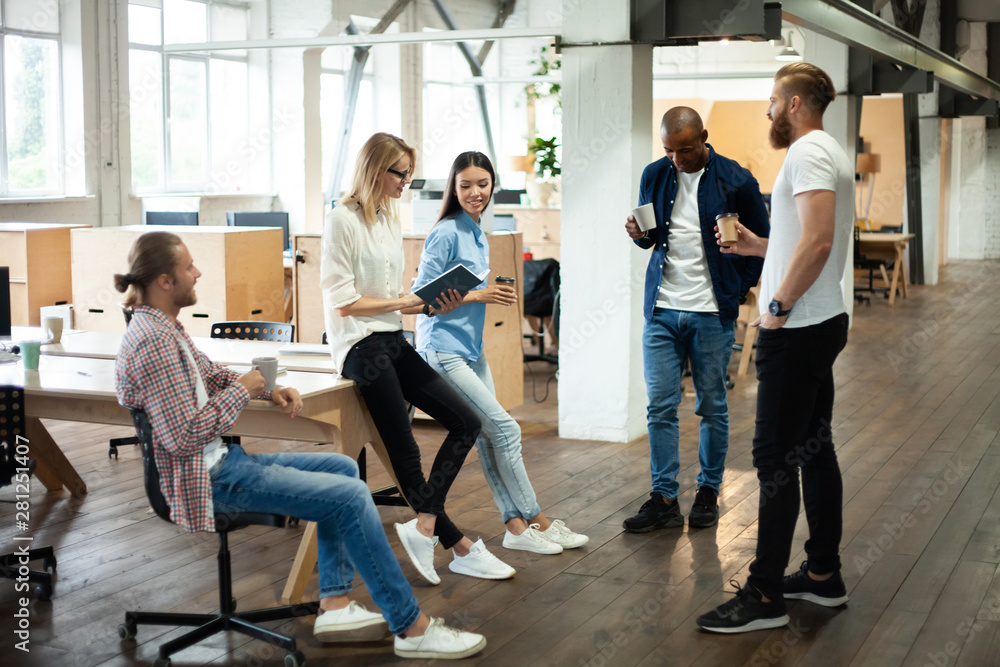 Young modern colleagues in smart casual wear working together while spending time in the creative office.