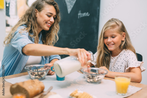 cute blonde girl having breakfast with her mother at home