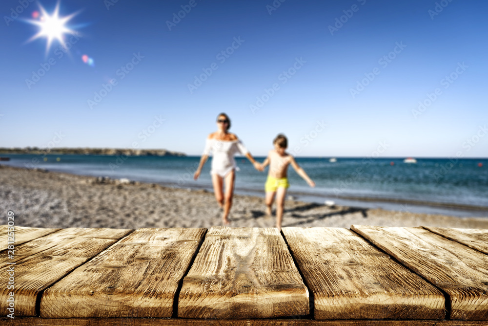 Table background with a mother with a kid girl playing and having fun on the sunny beach.