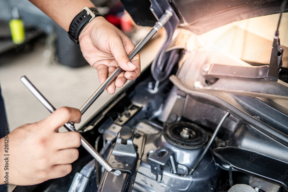 Obraz premium Male hand of auto mechanic fixing car hood and engine in the garage. Automobile industry concept