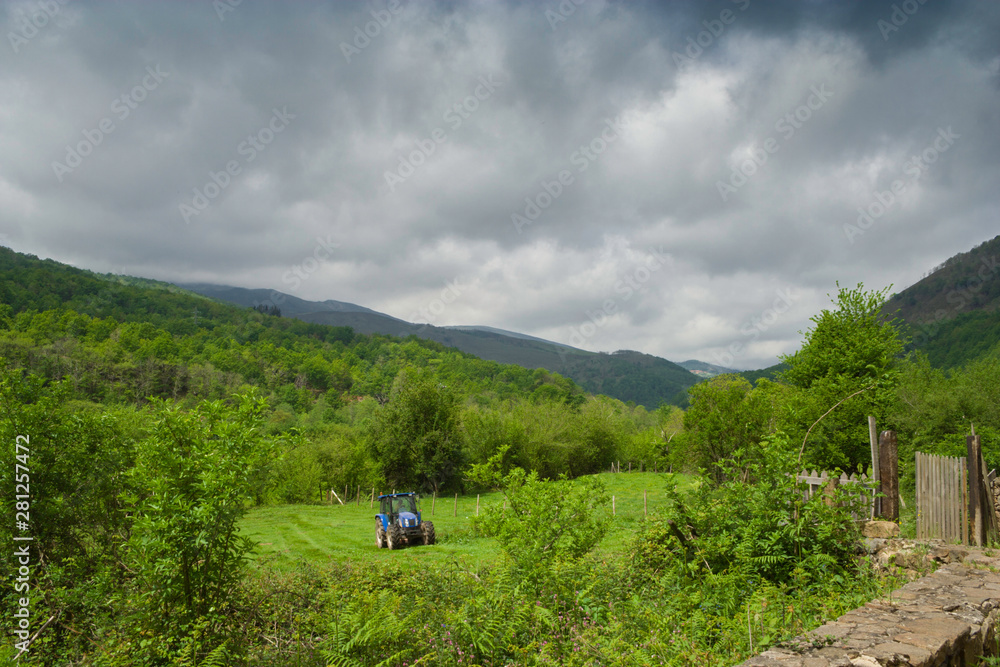 Farm tractor tilling green fields,agricultural landscape