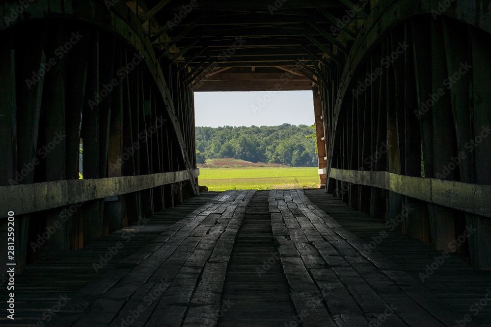 Fototapeta premium Looking through a covered bridge to the farm beyond, in Parke County, Indiana