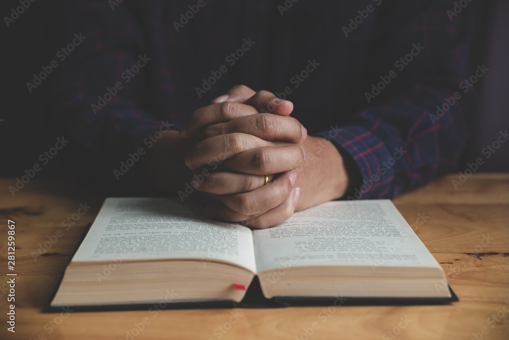 Naklejka premium Man studying the Holy Bible on a wooden table.