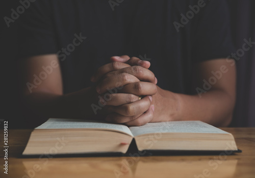 Man studying the Holy Bible on a wooden table.