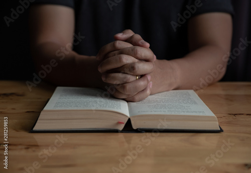 Man studying the Holy Bible on a wooden table.