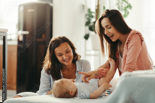 Φωτογραφία Two happy women having fun with their baby at home.