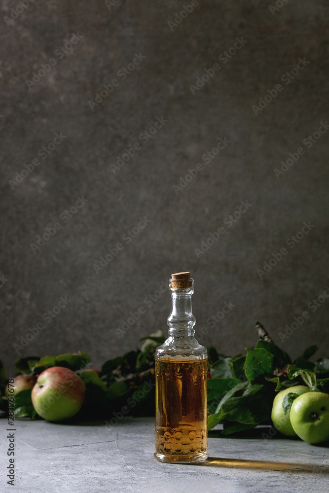 Variety of apple drinks. Bottles ang glasses of apple juice, vinegar and cider with garden apples with leaves and branches on table with dark background. Autumn home harvesting. Variety of apple drinks. Bottles ang glasses of apple juice, vinegar and cider with garden apples with leaves and branches on table with dark background. Autumn home harvesting.