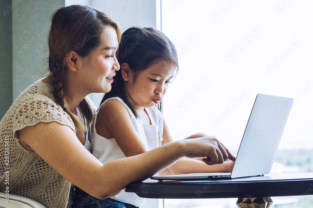 Mother and daughter using laptop together - obrazy, fototapety, plakaty 