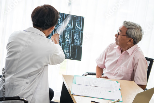 Expert doctor examining and explaining x-ray film to patient.